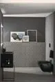 Schwarze Bidetarmatur an Wandmontage in modernem Badezimmer. Dazu dekorative Bilder an der Wand und grafische Fliesenmuster. Ideal Standard Design.